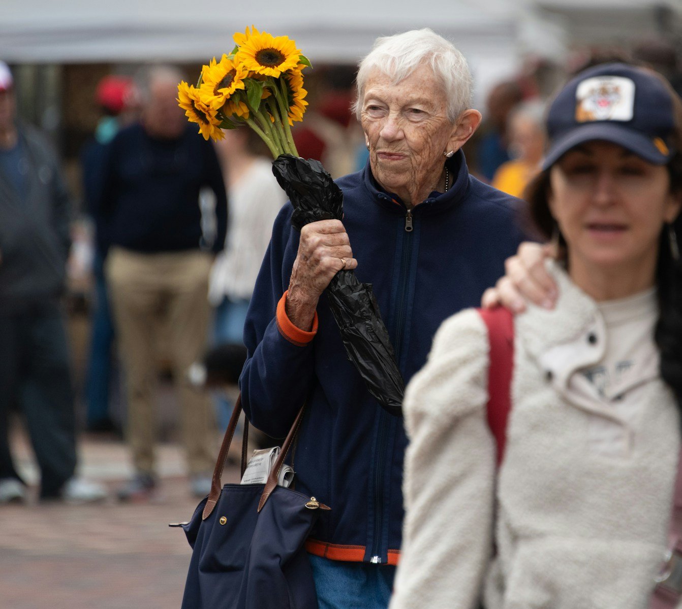 A man holding a bouquet of sunflowers while walking down a street